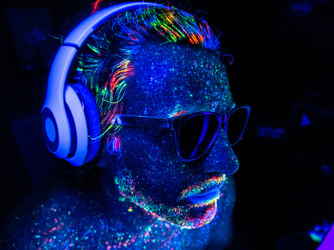 Male DJ with headphones under UV lights