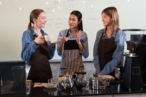 Group of young barista women discuss and working at the coffee shop. Group of female waitress training or meeting at coffee shop