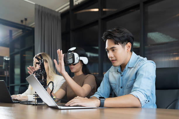 Male and female engineer working with vr glasses control AI robot arm system in workshop. Male engineer using laptop computer for control Programmable logic controller robotics arm system project ingeniero masculino y femenino que trabaja con gafas vr controlan el sistema de brazo robótico ai en el taller. ingeniero masculino usando computadora portátil para control controlador lógico programable proyecto de sistema de brazo robótico