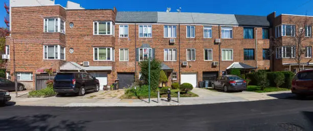 Red Brick Rowhouses in Bay Ridge Neighborhood of Brooklyn, New York, USA. Cars parked on the driveways next to the houses. Canon EOS 6D (full Frame Sensor) Camera and Canon EF 24-105mm F/4L IS lens. High resolution stitched panoramic image. 2.4:1 Image Aspect Ratio.