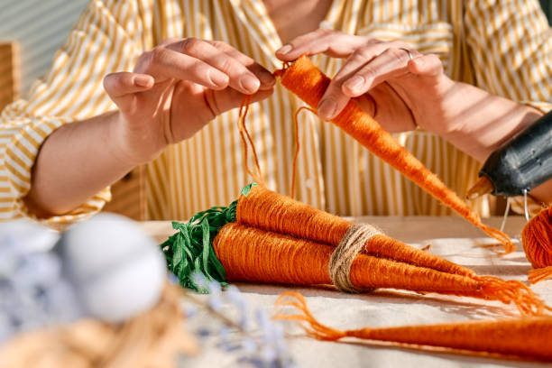 istock Woman making craft wool thread carrots for Easter decoration. Minimalist decor for Easter. DIY handmade craft project. 1468855368