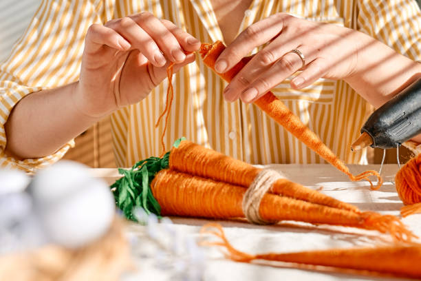 istock Woman making craft wool thread carrots for Easter decoration. Minimalist decor for Easter. DIY handmade craft project. 1468855373