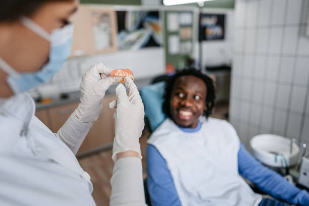 istock Young Female Dentist Holding Dentures  And Talking To Her Patient At The Dentist's Office 1468856471