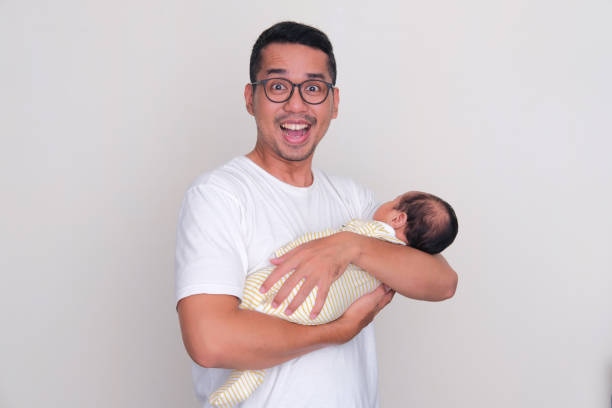 Asian father showing excited expression when holding his newborn babyAsian father showing excited expression when holding his newborn baby Asian father showing excited expression when holding his newborn baby keluarga stock pictures, royalty-free photos & images