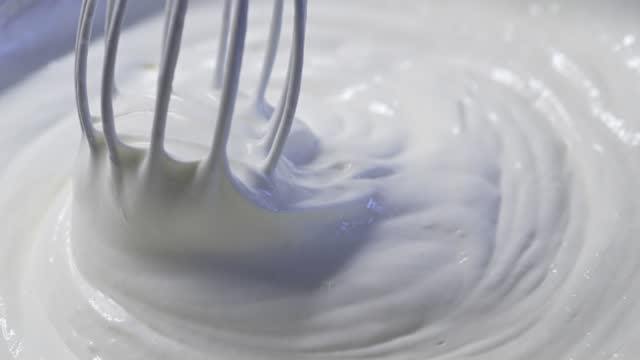 Whisk stirs the cream in a bowl