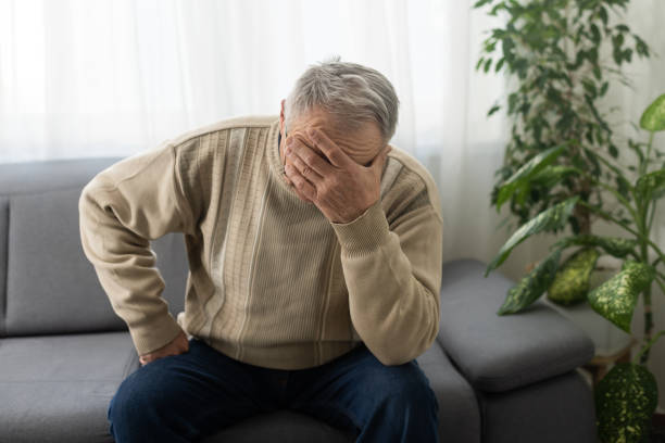 istock Senior man having headache and touching his head while suffering from a migraine in the living room, Mature man presses a hand to head suffers from unbearable pain. 1468857668