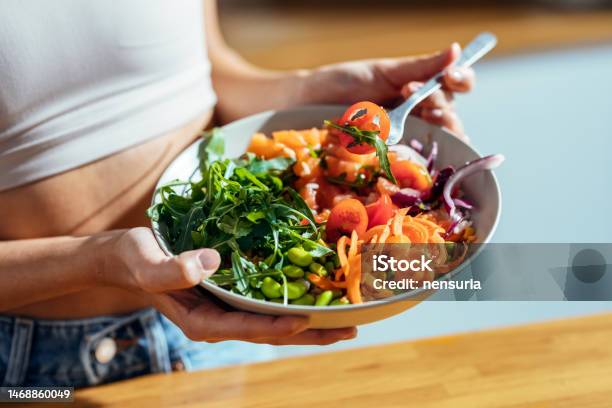Fitness Woman Eating A Healthy Poke Bowl In The Kitchen At Home Stock Photo - Download Image Now
