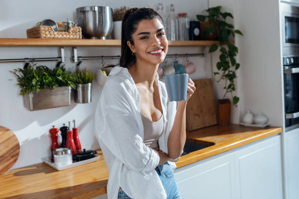 istock Beautiful young woman drinking coffee while standing in the kitchen at morning 1468860054