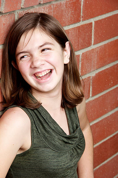 portrait of little indigenous girl leaning against the wall of a house with gestures of happiness and wearing purple clothing
