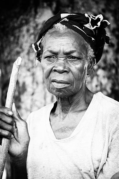 Old African woman holding stick and looking out of the frame.