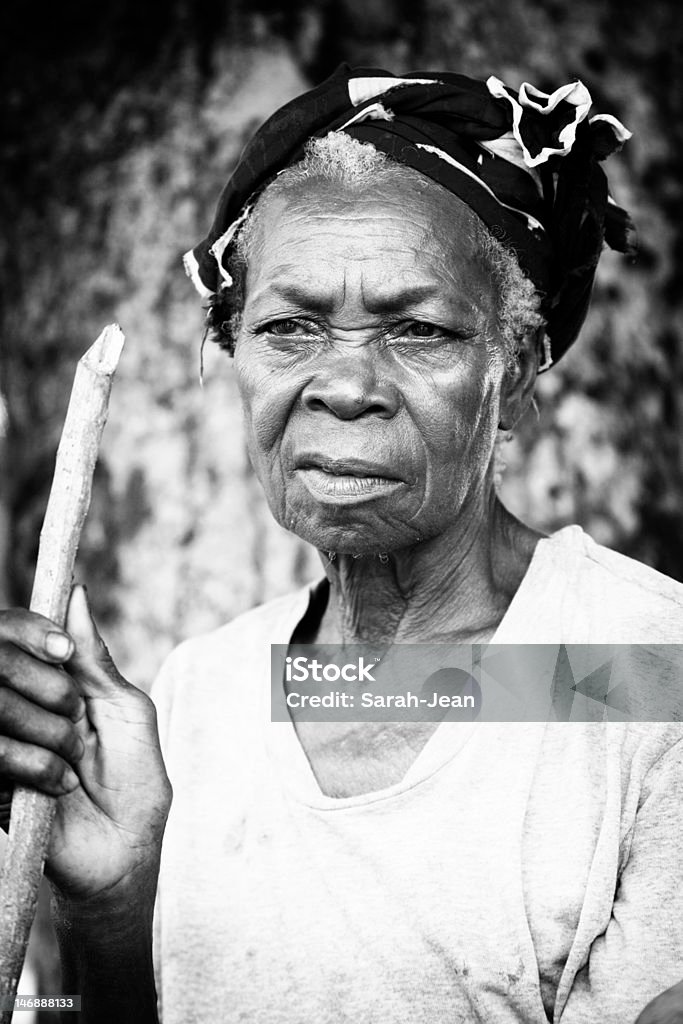 Old woman looking into the distance Old African woman holding stick and looking out of the frame. African Ethnicity Stock Photo