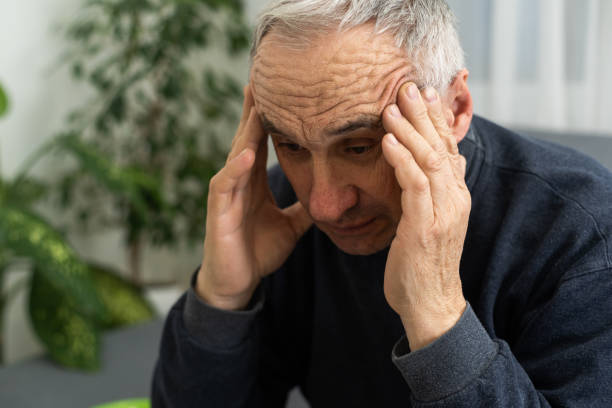 istock Senior man having headache and touching his head while suffering from a migraine in the living room, Mature man presses a hand to head suffers from unbearable pain. 1468882982