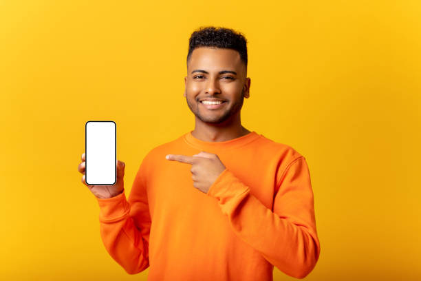 istock Surprised Indian man holding smartphone in hand and points finger at empty phone screen, astonishment guy presenting best deal, advertising new mobile app, isolated 1468888860