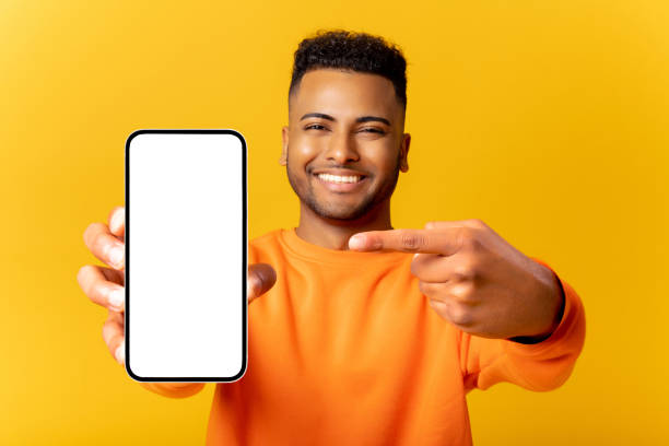 istock Surprised Indian man holding smartphone in hand and points finger at empty phone screen, astonishment guy presenting best deal, advertising new mobile app, isolated 1468888937