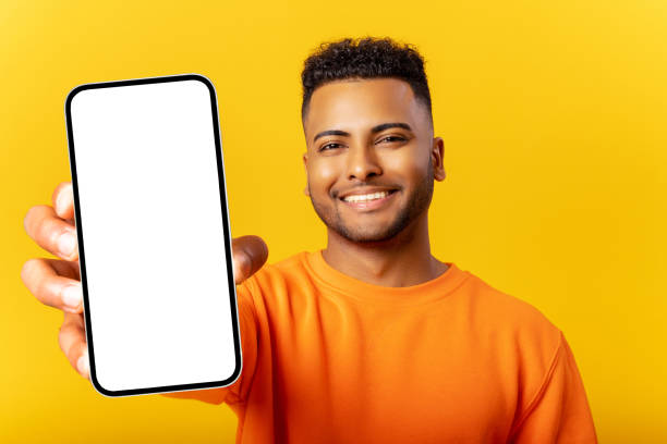istock Young indian man demonstrates smartphone with blank screen and rejoicing, guy likes mobile app, looking and smiling at the camera, feels satisfied 1468888943