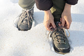 man tying his shoelaces in winter outdoors