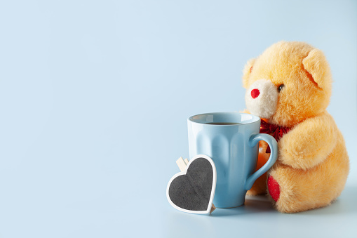 Fluffy teddy bear with  cup of coffee on blue background. Blue monday concept.