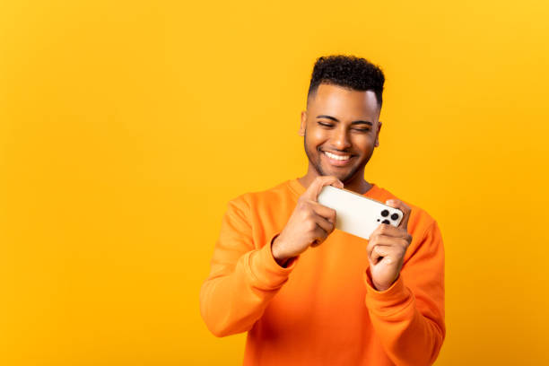 istock Happy Indian man in casual clothes using smartphone isolated on orange, positive guy chatting online, using new mobile app, playing mobile 1468889307