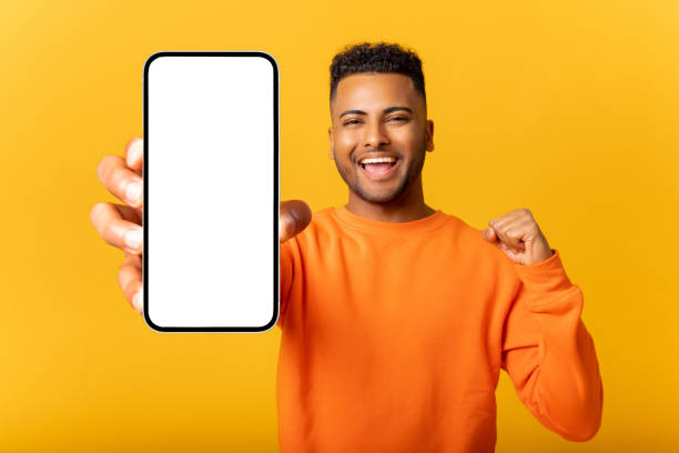 istock Young indian man demonstrates smartphone with blank screen and rejoicing, guy likes mobile app, looking and smiling at the camera, feels satisfied 1468889335