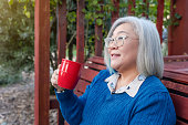 Asian woman drinking coffee in garden