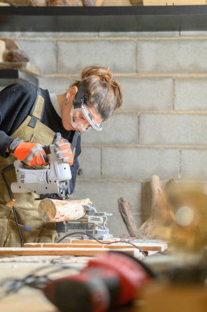 vertical photo of woman carpenter sanding a piece of wood - independence business women manual worker imagens e fotografias de stock