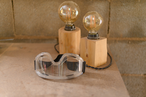 Wooden lamps next to a protective work goggles in a wood workshop