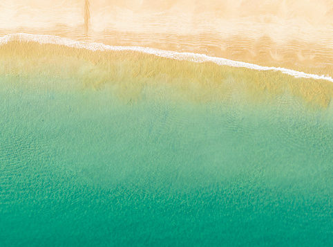 Gentle waves coming into an idyllic sandy beach on New Zealand's Coromandal Peninsula. Photographed from the air.