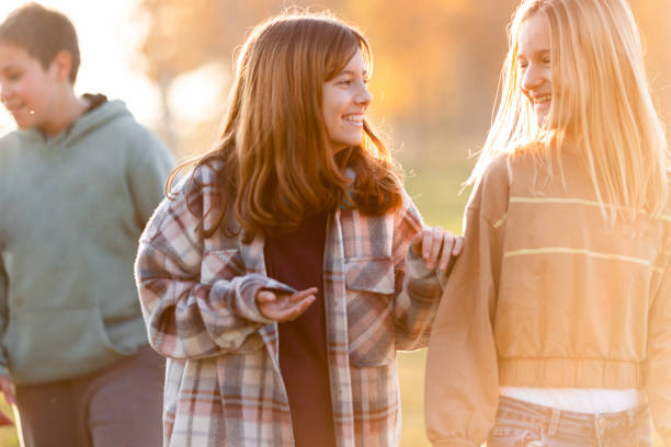 Two happy tennage girls walking and talking in public park