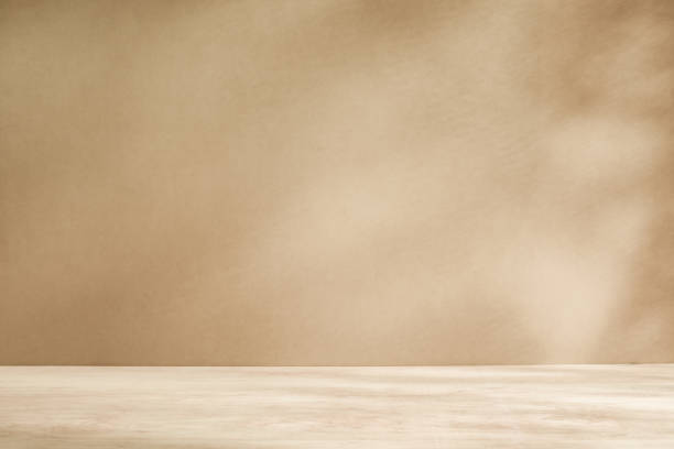 istock Wooden table with light and subtle texture, against beige or cream wall with sunlight 1468898198