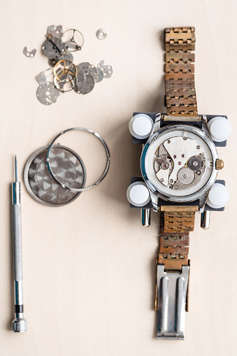 above view of old wristwatch with rusty bracelet on wooden table in watchmaker workshop