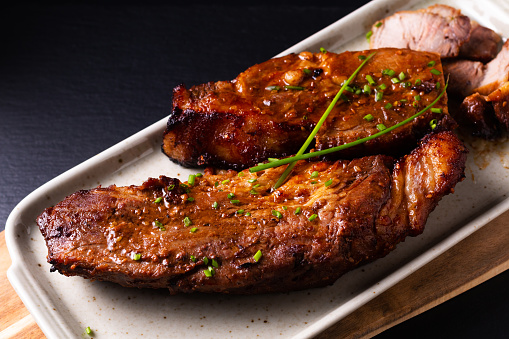 Roast pork loin, cooked potatoes and fresh vegetables on wooden table