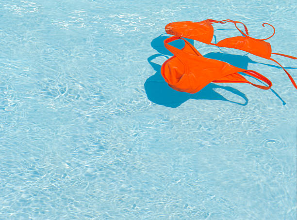 Orange bikini swim suit in a swimming pool. Copyspace background. stock photo