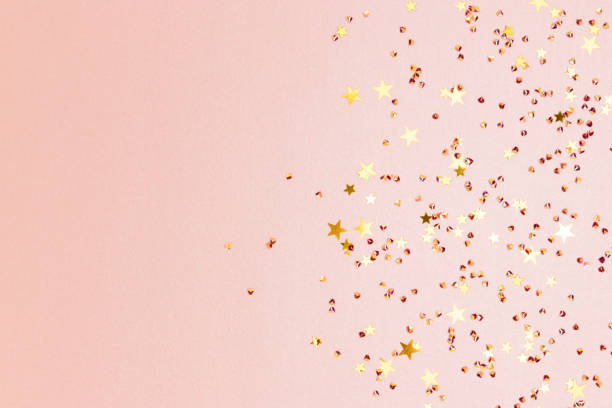 istock Gold colored stars and crystals confetti on a pink glittering background. 1468910446