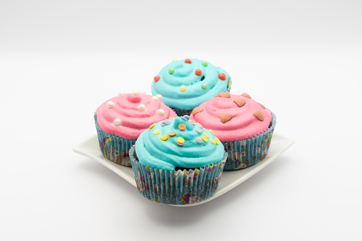 Turquoise and pink cupcakes on a small plate with white background