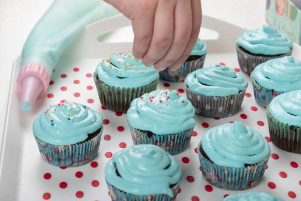 A girl is decorating a cupcake with colorful pearls