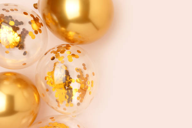 istock Gold colored inflatable balloons with confetti inside on a beige background. 1468911170