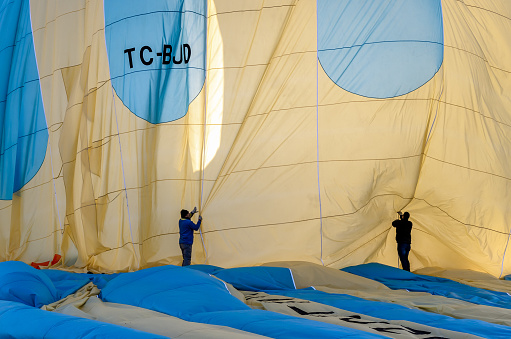 Goreme, Turkey - November 12, 2017: Two assistants fold the fabric of the hot air balloon that landed after the flight at a great tourist attraction of spectacular Cappadocia