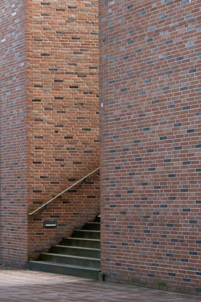 Semi-concealed staircase with metal railing between two very high red brick and clinker walls
