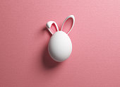 Easter egg and rabbit ear on pink color background