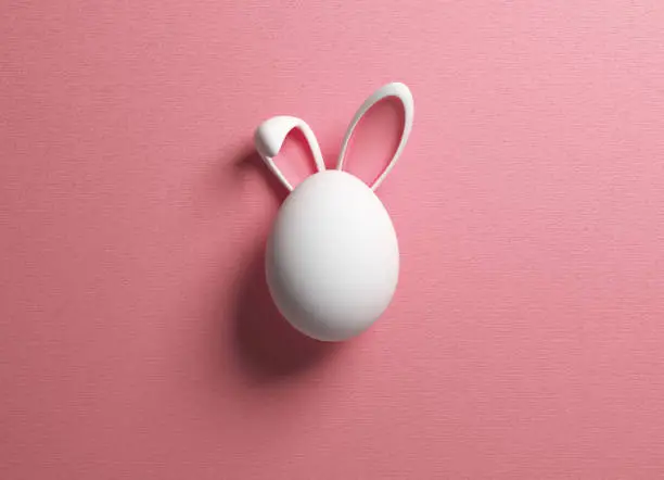 Photo of Easter egg and rabbit ear on pink color background