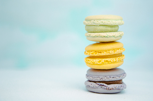 Close up of three fresh macarons stacked up with pastel blue background