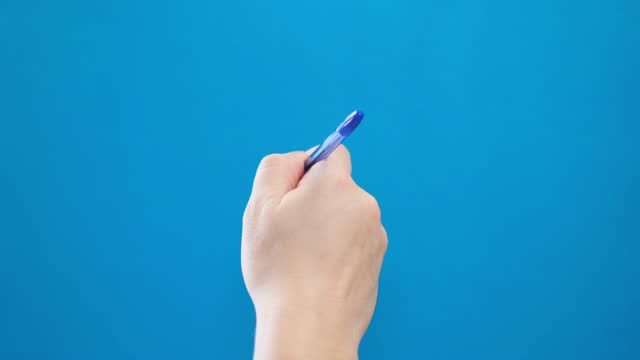 Male hand writing with a ballpoint pen in short strokes on a blue background.