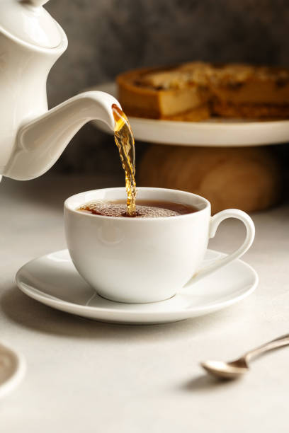 istock Pouring hot tea in white, ceramic cup, served with cake 1468915963