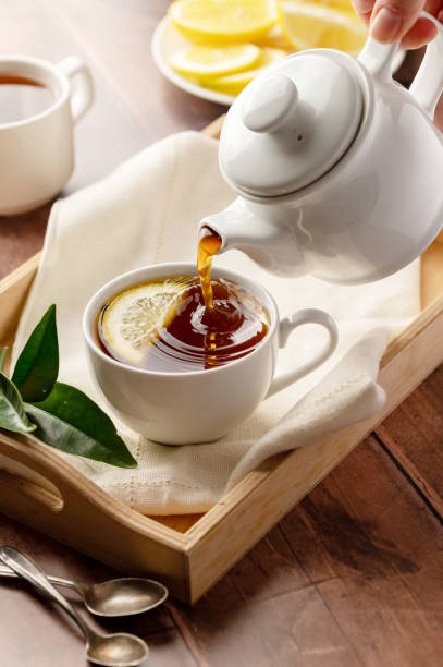 istock Black tea, pouring tea from tea pot in a white, ceramic cup. Wooden, rustic background 1468917135