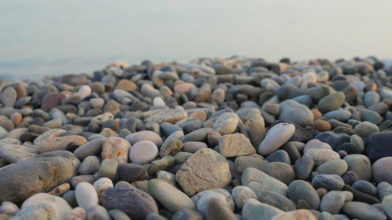 closeup of pebble beach and sea in background, little stones on coast of river or lake