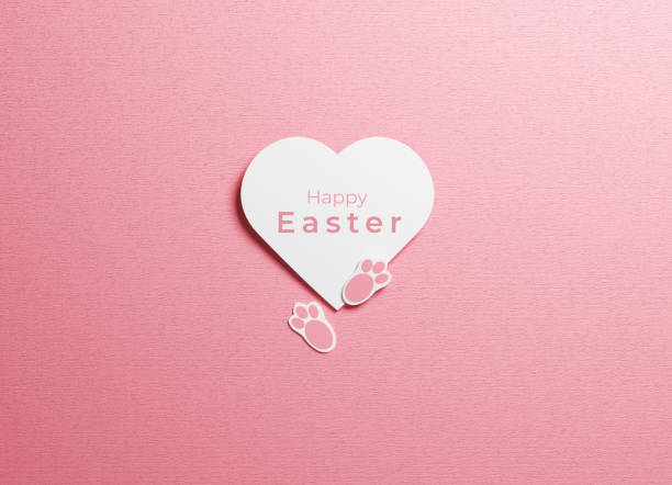 Easter concept  white heart shape rabbit paw and happy Easter text on pink color background