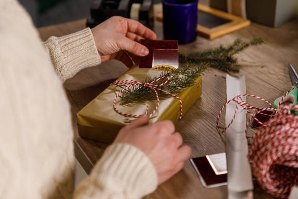 istock Young man wrapping and tying decorative twine around a Christmas gift box 1468924557