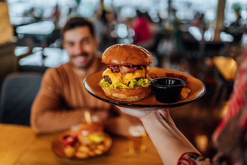 Waitress carrying a plate with a freshly made burger