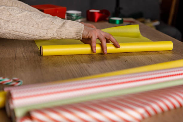 istock Young man sitting at table and unrolling a roll of wrapping paper 1468924697
