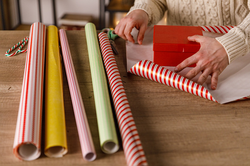 Close up shot of crafty young man measuring how much wrapping paper is going to take to wrap a gift box.